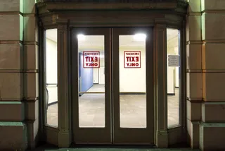 Glass double doors at night with red 'Emergency Exit Only' signs, seen in reverse from outside.